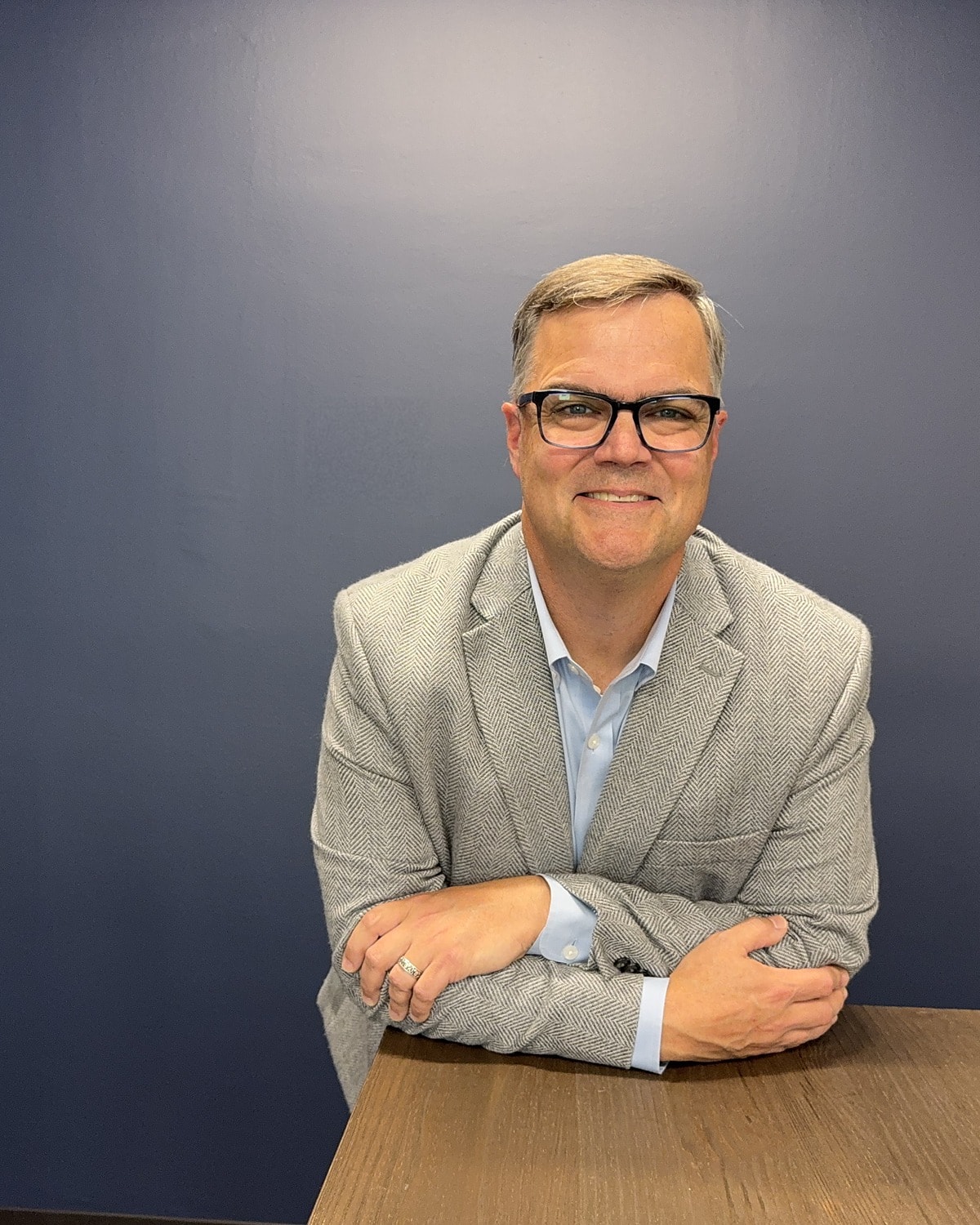 Brian Hanley leaning forward on a conference table, smiling